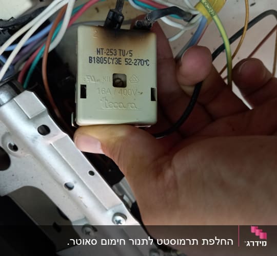 יד מחזיקה רכיב חשמלי עם חוטים צבעוניים